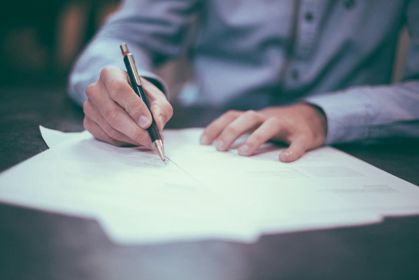 A person signing legal papers at a desk